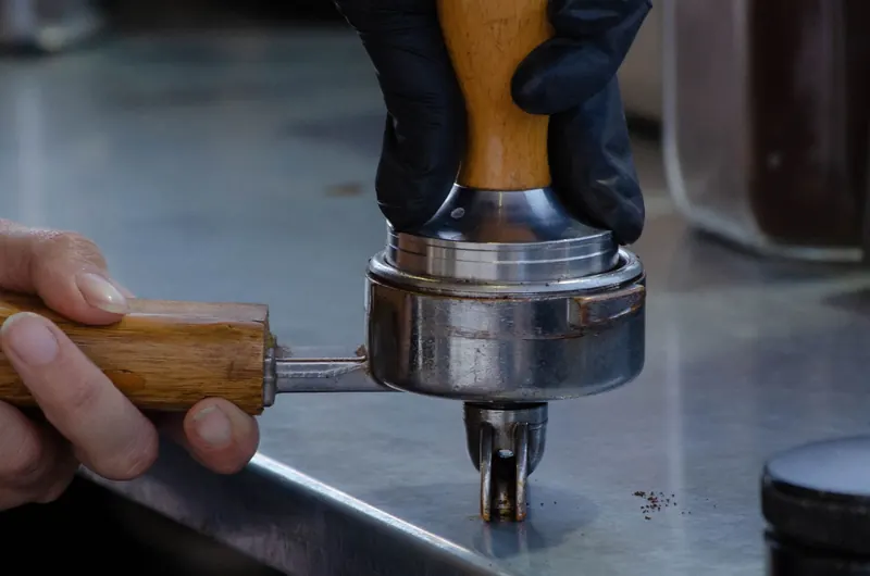 Detailed view of barista hands tampering coffee grounds. Perfect for coffee enthusiasts