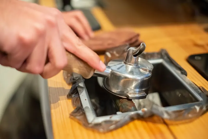 Detailed view of a portafilter being cleaned in a knock box, ideal for coffee-related themes