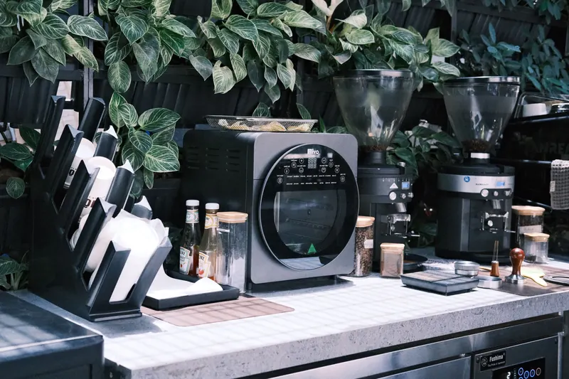 Stylish café kitchen with modern coffee machines and lush green plants