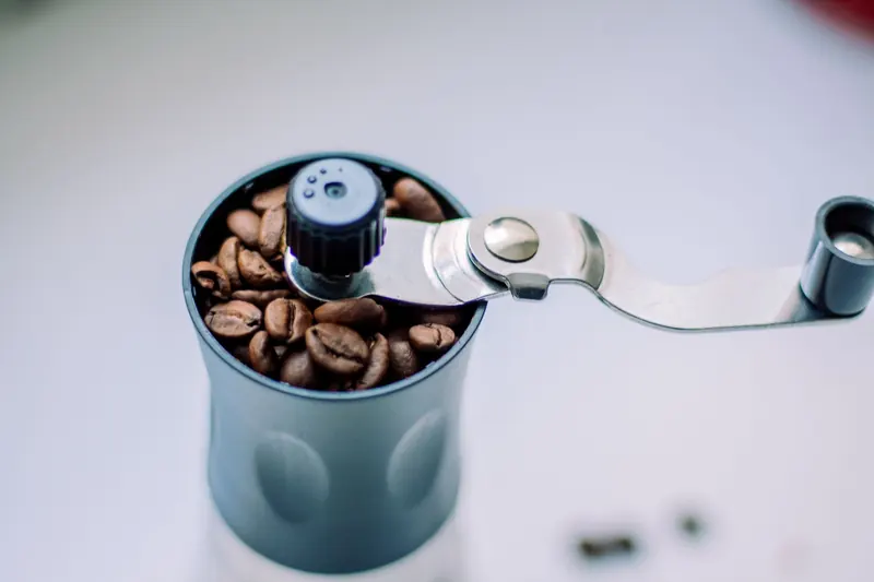 Close-up of a manual coffee grinder filled with coffee beans