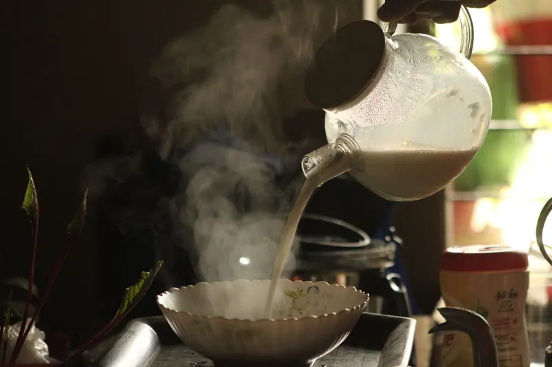 Warm morning light illuminates steaming milk being poured into a bowl